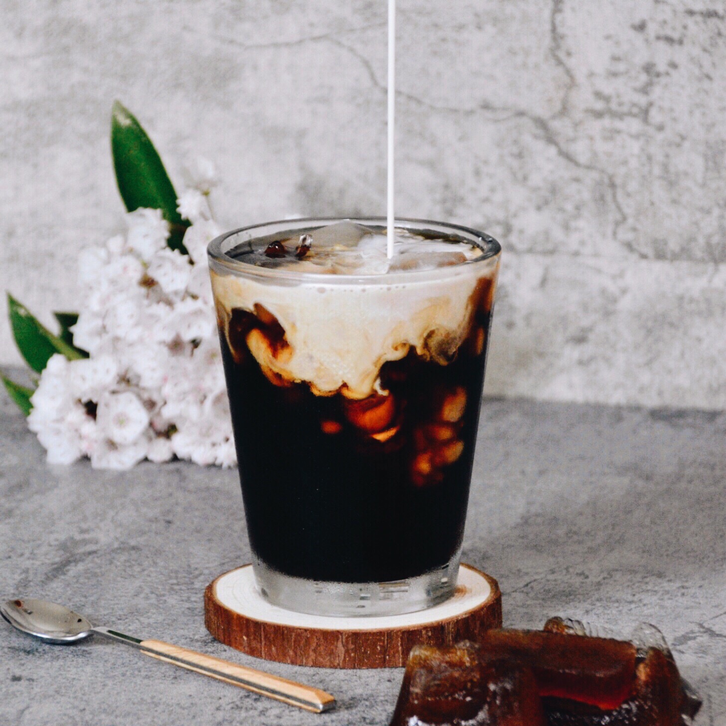 cold brew coffee with milk pouring from top and coffee ice cubes