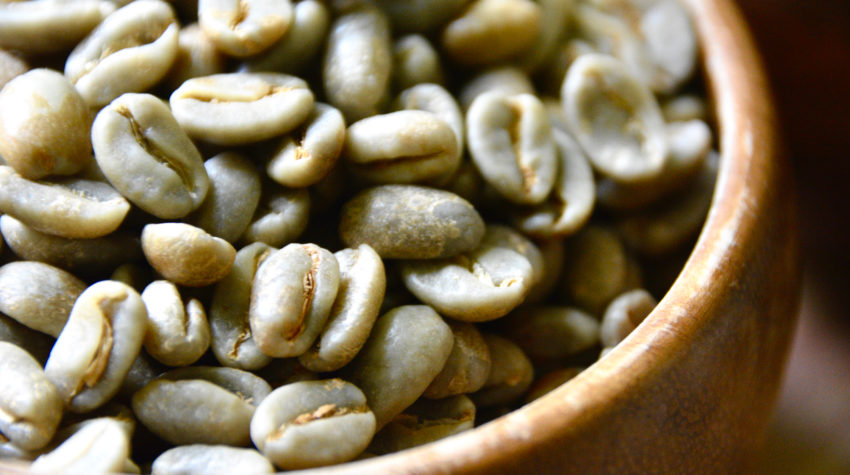 green coffee beans in a wooden bowl