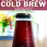 ovalware cold brew maker on a wooden table with fall flowers in the background with blue windows