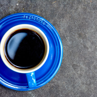 blue coffee cup with saucer on cement pavement