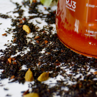 Ovalware cold brew maker filled with chai tea with chai tea leaves on the background