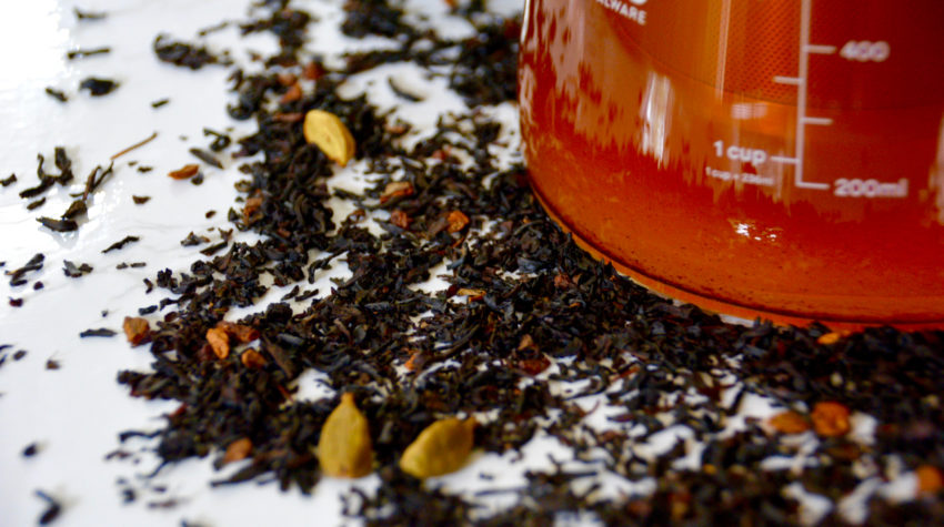 Ovalware cold brew maker filled with chai tea with chai tea leaves on the background