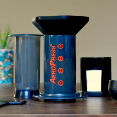 Aeropress separated into components sitting on a table with a succulent in background