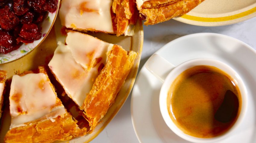 Overhead view of Wisconsin kringle and a cup of coffee on a table, styled as a cozy breakfast at home.