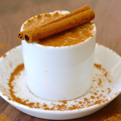 chai latte in a white cup with a cinnamon stick