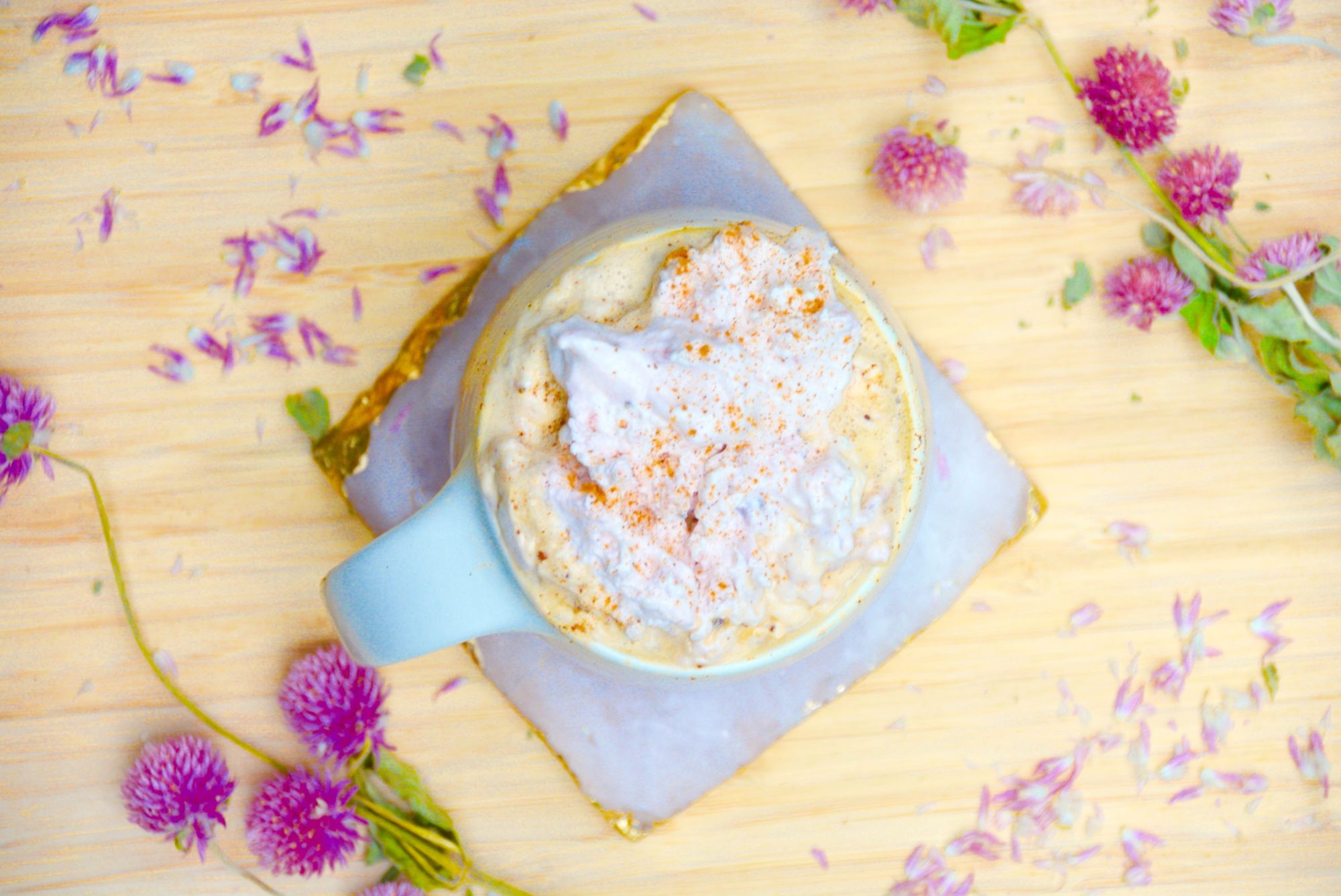 Flay lat of strawberry coffee latte with dried pink flowers on wood