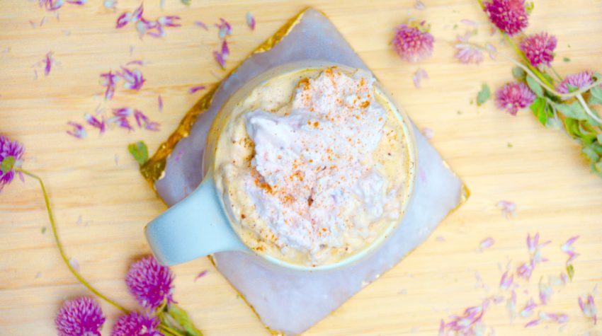 Flay lat of strawberry coffee latte with dried pink flowers on wood