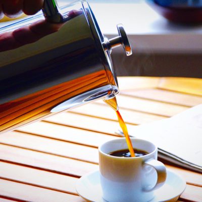 french press pouring coffee into a small white mug