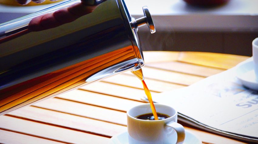 french press pouring coffee into a small white mug